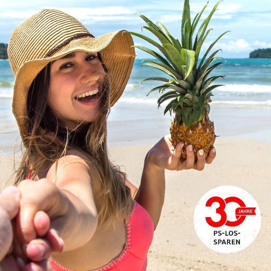Eine Frau mit einer Ananas in der Hand am Strand